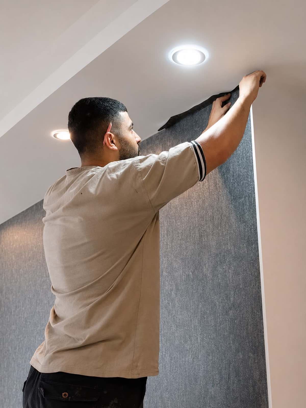 Professional wallpaper installer aligning wallpaper on a feature wall in Dubai