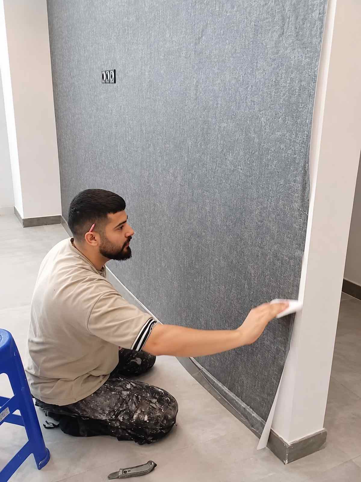 Wallpaper installer smoothing and trimming wallpaper during installation in Dubai