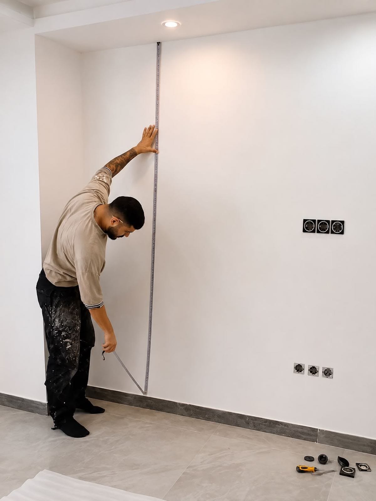 Wallpaper installer measuring a wall before installation in Dubai